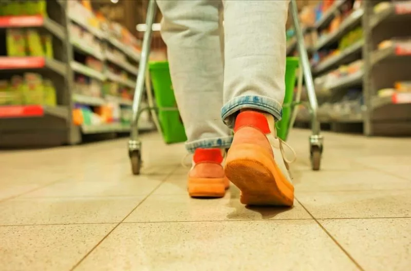 Floor level shot of person shopping in supermarket pushing trolley